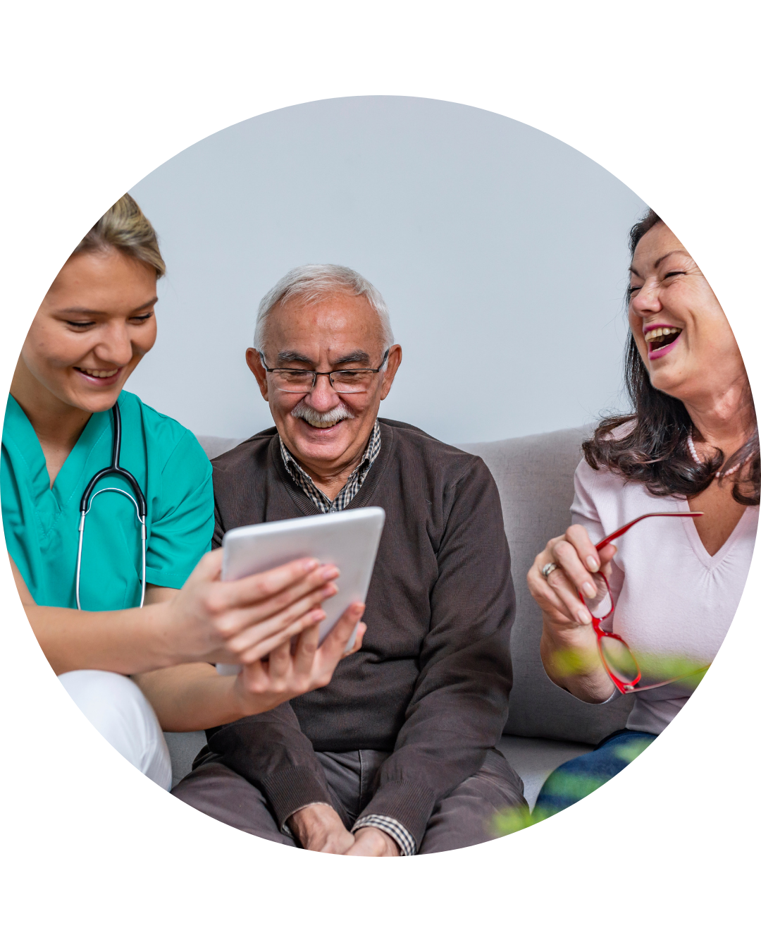 A health care professional holding a tablet while sitting with a patient and a patient partner.